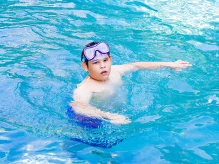 Teenager boy wearing mask swimming in the pool. Happy holiday sunlight concept.
