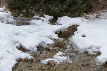 Fototapeta na wymiar small frozen creek in a winter mountain landscape