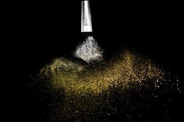 Cosmetic brush with golden cosmetic powder spreading for makeup artist and graphic design in black background, look like a luxury mood.
