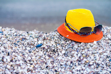 Fashionable hat with glasses are on the sea shells. Concept of tourist recreation on the sea beach