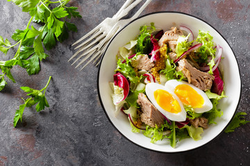 Diet food tuna salad with boiled egg, canned fish, onion and green lettuce top view