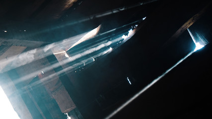 Suns rays shine through the gap in the wooden door, the smoke in the dark building glows