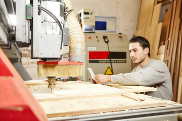Man compares the CNC machine with the drawing. Device with numerical control.