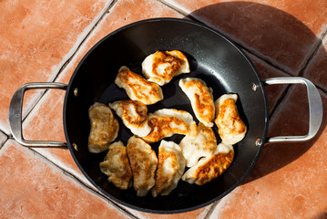 Flat lay image above traditional polish meal pirogi in the frying pan on the table. Delicious dough meal prepared on old way