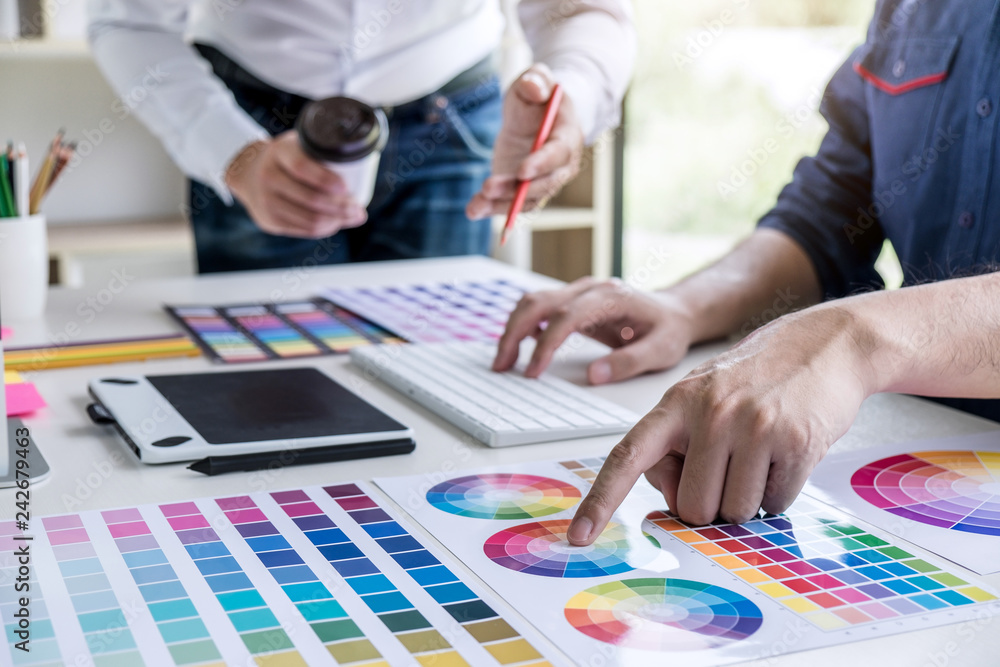Poster Two colleagues creative graphic designer working on color selection and drawing on graphics tablet at workplace
