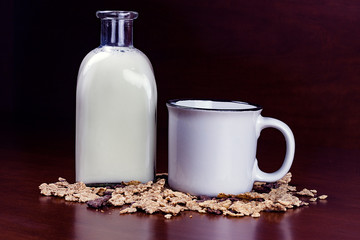 BOTELLA DE LECHE, TAZA BLANCA DE DESAYUNO Y CEREALES SOBRE FONDO OSCURO