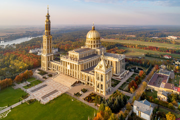 Sanctuary and Basilica of Our Lady of Licheń in small village Lichen. The biggest church in Poland, one of the largest in the World. Famous Catholic pilgrimage site. Aerial view in fall. Sunset light - obrazy, fototapety, plakaty