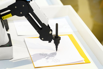 Robotic hand with a pencil draws simple graphic drawings on white paper. Future and art concept.