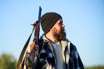 Man brutal bearded guy gamekeeper blue sky background. Hunter with rifle gun close up. Guy bearded...