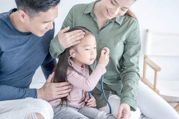 asian family happy people concept - mother and father help their daughter do homework in living room