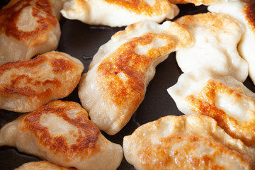 Closeup macro image of dough meal in frying pan. Preparing traditional dough meal. Food preparing concept. Polish pirogi meal in the frying pan