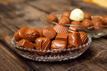 Chocolate candies in crystal bowl on old vintage rustic table