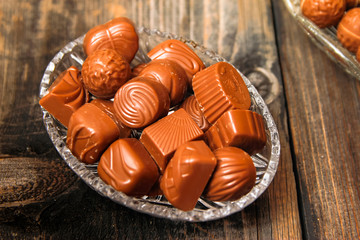Chocolate candies in crystal bowl on old vintage rustic table
