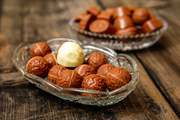 Chocolate candies in crystal bowl on old vintage rustic table