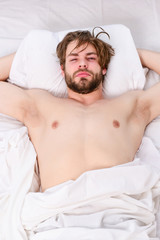 Fototapeta na wymiar Handsome man using clock in bed after waking up in the morning. Stretch after wake up in the morning. Waking up energy.
