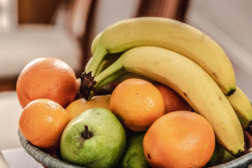 Fruit bowl containing banana, oranges, mandarin and pears on the table. Healthy lifestyle.