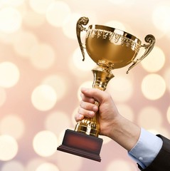 Hand holding golden trophy on blurred background