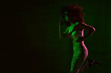 Young sport woman with afro hairstyle running jogging in gyn in green and pink neon light