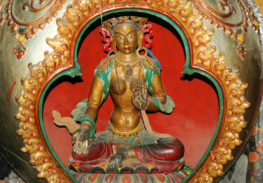 Ancient statue of a Tibetan female deity with a golden body in the lotus position in a monastery in Tibet