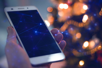 man with smartphone mobile for social network internet with merry christmas light of tree