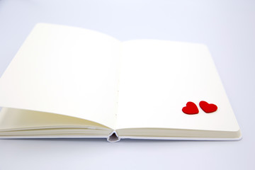 Two small hearts in the coner of blank notebook on white isolated background.