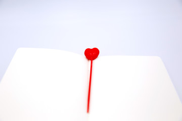 Big heart shaped bookmark in white notebook on white isolated background.