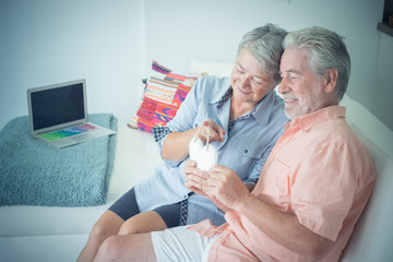 adult mature caucasian silver society couple in love at home enjoying the leisure time sitting on...