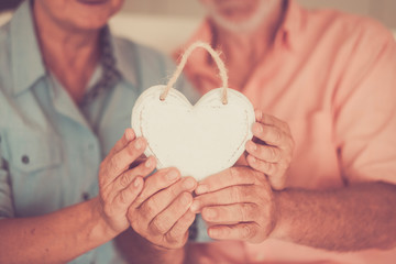Happy married aged mature couple holding together a white wood hand made shabby chic hearth and...