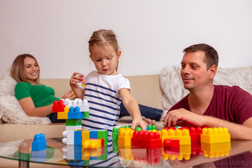 Smiling father and little daughter playing with cubes together at home.
