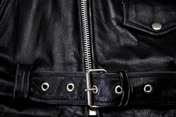 Detail of old black leather police style motorcycle jacket focusing on belt and zipper, showing flap pocket also.