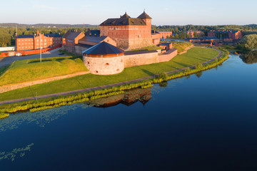 Old fortress on the shore of Lake Vanajavesi in the rays of the rising sun. Hameenlinna, Finland