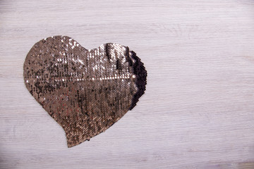 Heart of shiny beads on a light wooden background