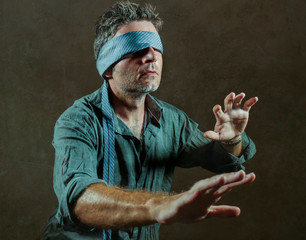 young lost and confused man blindfolded with necktie playing internet trend dangerous viral...