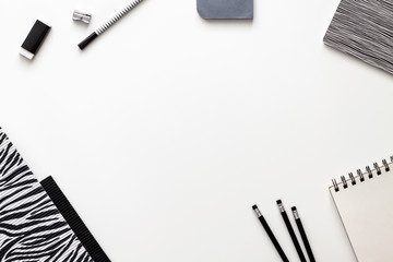 Creative desk with office supplies. Papers, notebook, sketchbook, pencils and felt-tip pens. Copy space for text. View from above. Black and white composition