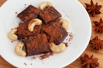 Broken dark chocolate with cocoa powder and cashew nuts and star anise