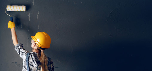 a strong-willed woman in a construction helmet, mittens, goggles and overalls is engaged in repair...