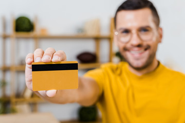 selective focus of credit card in hand of cheerful man