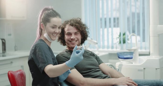 At Dentist Young Patient After A Oral Hygiene Procedure Doctor Giving To Him Some Medicine To Using A Home And Explain The Instructions To Be Used He Is Very Confused And Smiling At The Same Time