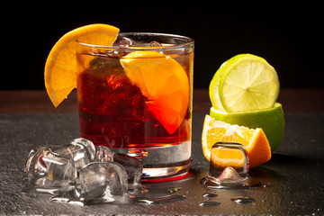 Cocktail rosso con ghiaccio e fette di limone in primo piano
