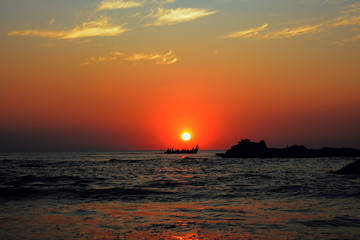 Boat with fishermen on the background of the sunset on the sea.