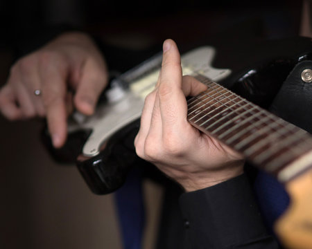 Male hands playing on electric guitar, close up, selected focus