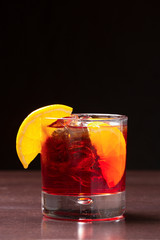 Cocktail rosso con ghiaccio e fettine di limone in primo piano