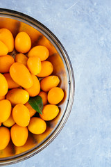 kumquat fruits on a   silver bowl on a gray concrete board,top view,natural light