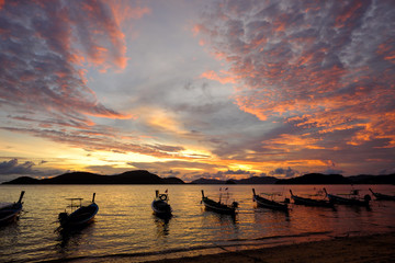 Naklejka na ściany i meble Silhouette of Long tail boats at sunset beach. Panwa Cape, Phuket Province, Thailand.