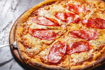 Italian Pepperoni pizza with mozzarella cheese and salami on wooden board. Close up
