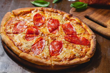 Italian Pepperoni pizza with mozzarella cheese and salami on wooden board. Close up