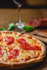 Italian Pepperoni pizza with mozzarella cheese and salami on wooden board. Close up