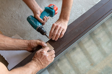 Cropped photo of two workman screw window frame