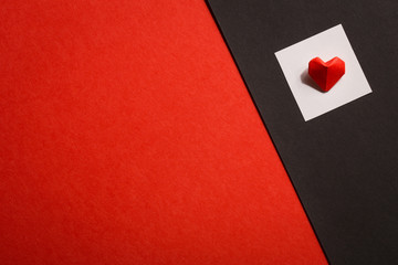 bulk origami heart out of red paper on a white square . red-black background