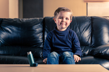 little boy in sofa and with asthma inhaler